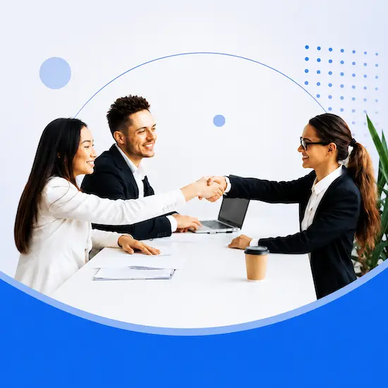 Three people shaking hands across a desk at the end of an interview